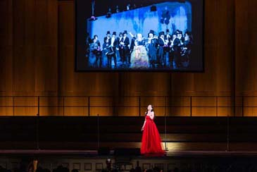 San Francisco Opera's "100th Anniversary Concert" with Adela Zaharia performing an aria from Gounod's "Roméo et Juliette" below an archival San Francisco Opera image (Ellie Dehn in Massenet's "Manon," 2017). Photo: Drew Altizer Photography